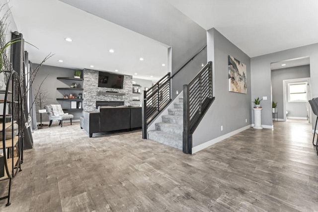 unfurnished living room with a stone fireplace and hardwood / wood-style flooring