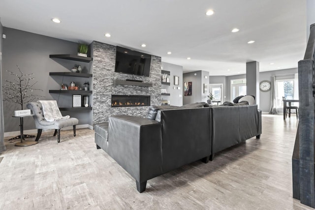 living room with a stone fireplace and light hardwood / wood-style floors