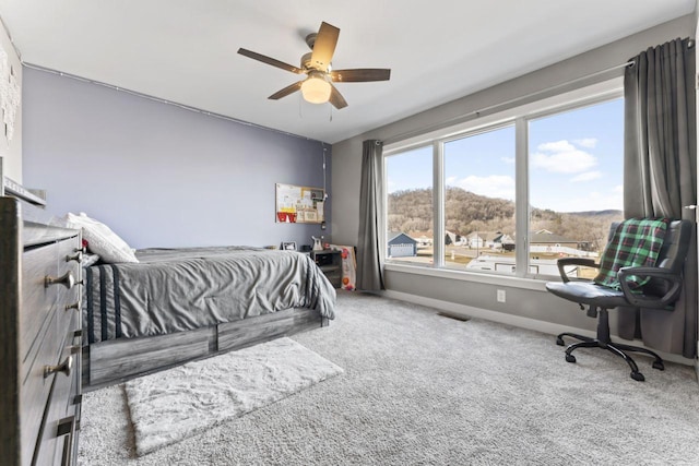 carpeted bedroom featuring a mountain view and ceiling fan