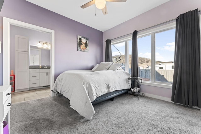 bedroom featuring ceiling fan, light colored carpet, and ensuite bath