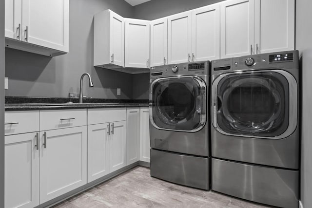 laundry room featuring cabinets, light hardwood / wood-style flooring, and separate washer and dryer