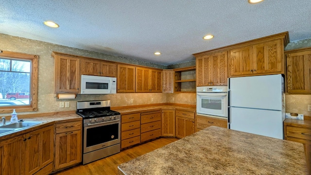 kitchen with light wood finished floors, open shelves, brown cabinetry, a sink, and white appliances