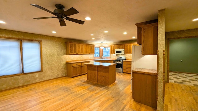 kitchen with light wood-style flooring, a kitchen island, stainless steel gas range oven, and white microwave