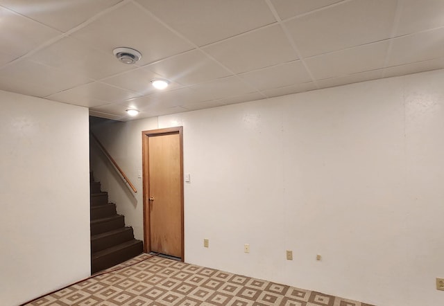 finished basement with a paneled ceiling and stairs