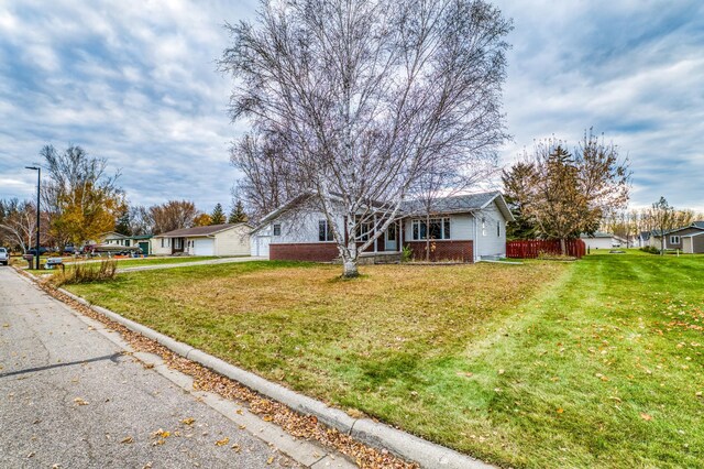 view of front of home with a residential view, brick siding, fence, and a front lawn