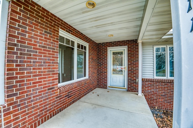 property entrance with covered porch and brick siding