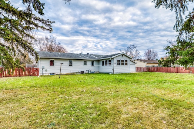 rear view of house featuring a lawn and fence