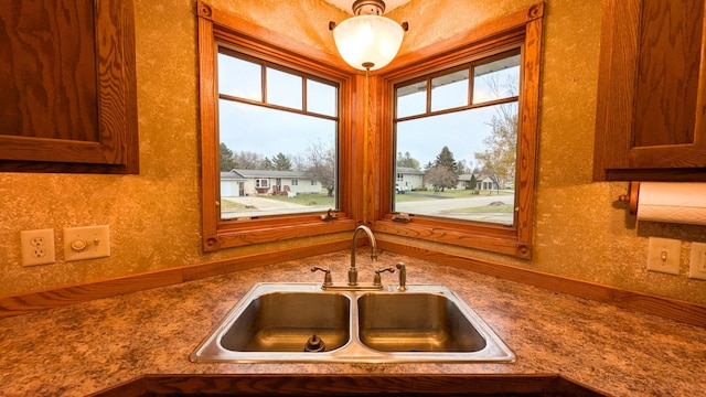 kitchen with dark countertops, a residential view, brown cabinetry, and a sink