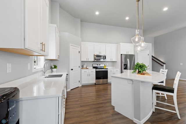 kitchen with dark hardwood / wood-style flooring, stainless steel appliances, sink, pendant lighting, and white cabinets