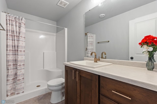 bathroom featuring tile patterned floors, vanity, toilet, and walk in shower