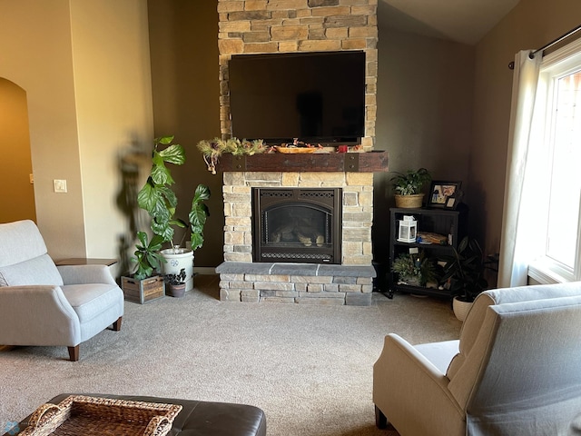 carpeted living room featuring a stone fireplace and a wealth of natural light