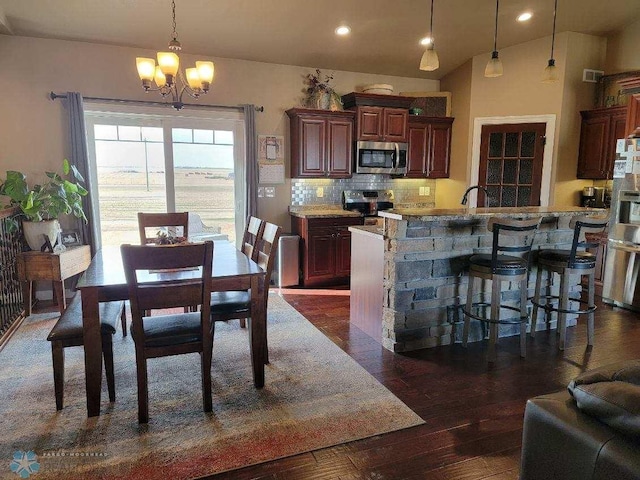 dining space with dark hardwood / wood-style flooring, an inviting chandelier, vaulted ceiling, and sink