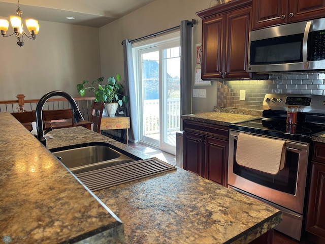 kitchen featuring sink, hanging light fixtures, stainless steel appliances, tasteful backsplash, and a chandelier