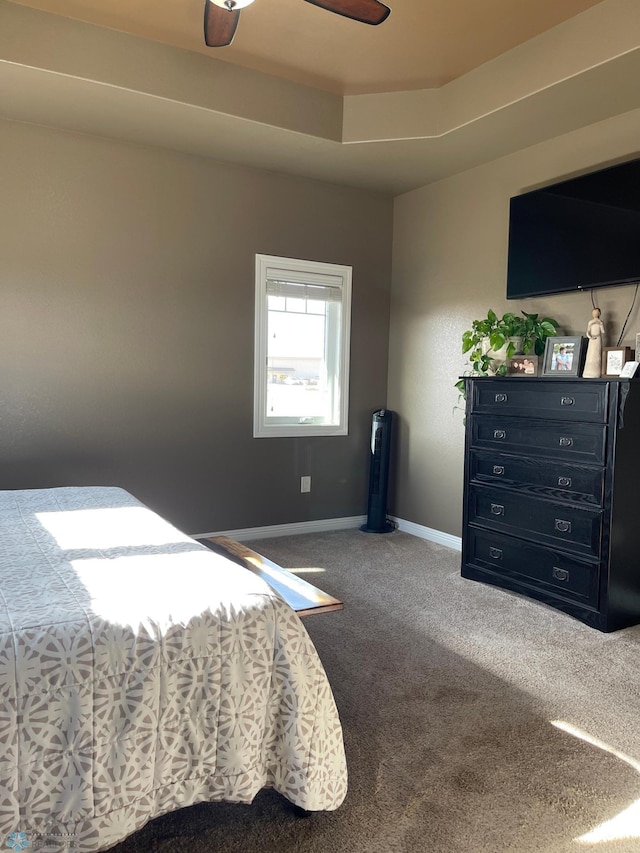 carpeted bedroom with a raised ceiling and ceiling fan