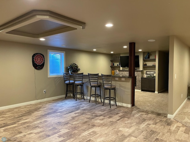 kitchen featuring light wood-type flooring, kitchen peninsula, a breakfast bar area, and dark brown cabinetry