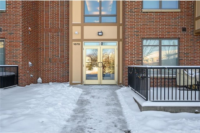 snow covered property entrance featuring french doors