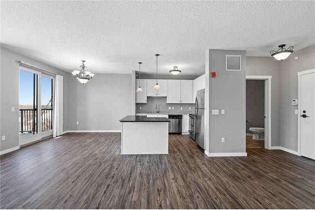 kitchen with dark hardwood / wood-style floors, a chandelier, decorative light fixtures, white cabinets, and appliances with stainless steel finishes