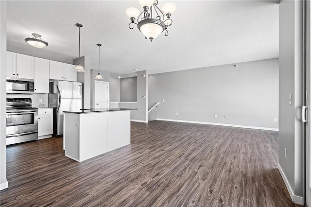 kitchen featuring stainless steel appliances, white cabinetry, hanging light fixtures, and dark hardwood / wood-style floors