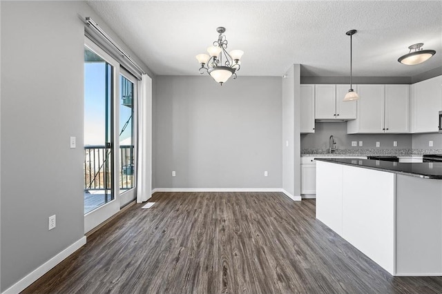 kitchen featuring white cabinets, a healthy amount of sunlight, a notable chandelier, and sink