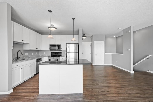 kitchen featuring a center island, sink, hanging light fixtures, white cabinetry, and stainless steel appliances