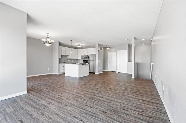 unfurnished living room featuring sink, a chandelier, and dark hardwood / wood-style floors