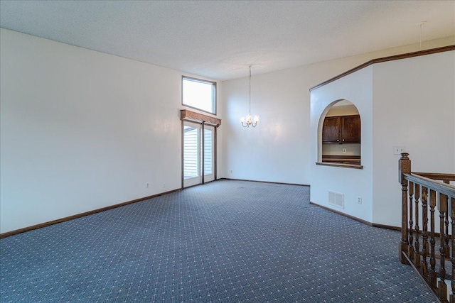 spare room featuring carpet, a textured ceiling, and a chandelier