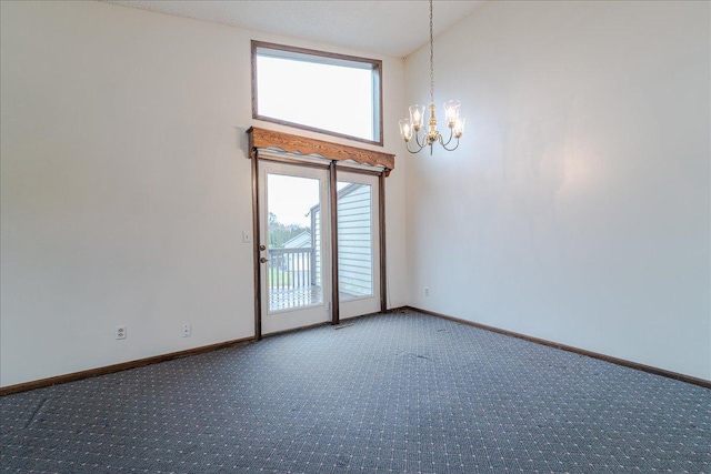 carpeted empty room with a chandelier and lofted ceiling