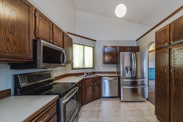 kitchen with lofted ceiling, crown molding, sink, light tile patterned floors, and stainless steel appliances