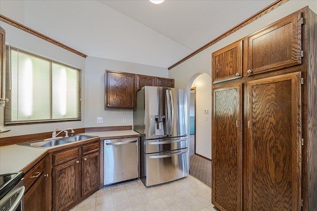 kitchen with appliances with stainless steel finishes, vaulted ceiling, ornamental molding, and sink