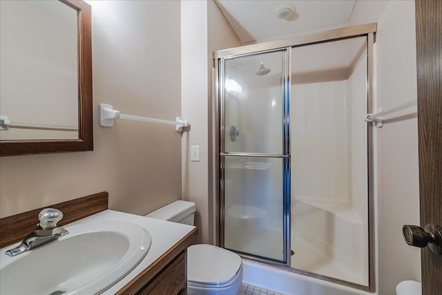 bathroom with a shower with door, vanity, a textured ceiling, and toilet