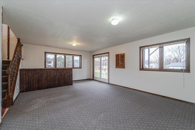 unfurnished room featuring carpet, a healthy amount of sunlight, and a textured ceiling