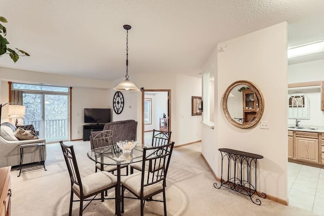 carpeted dining room with a textured ceiling and sink