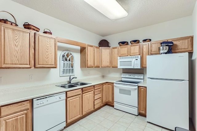 kitchen with a textured ceiling, sink, white appliances, and light brown cabinets