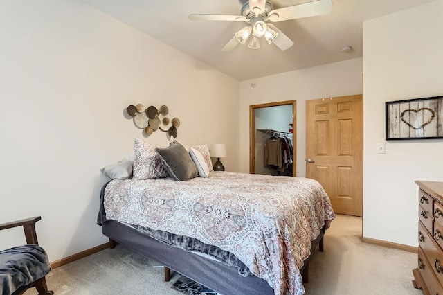 bedroom featuring a spacious closet, a closet, ceiling fan, and light carpet