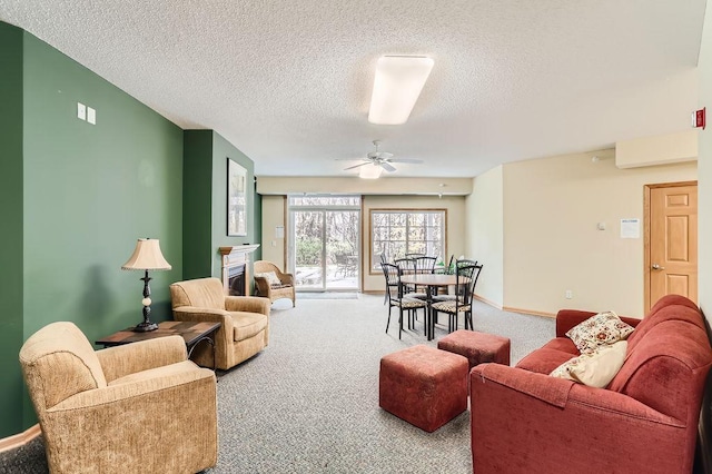 living room with ceiling fan, carpet floors, and a textured ceiling