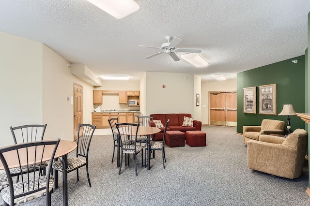 dining space with a textured ceiling, carpet floors, and ceiling fan