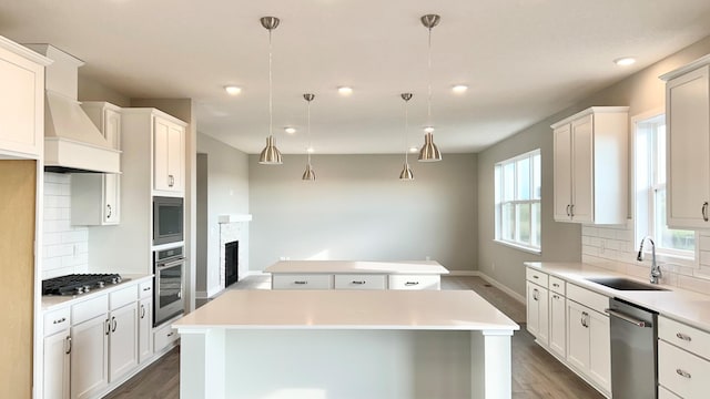 kitchen featuring appliances with stainless steel finishes, tasteful backsplash, hanging light fixtures, a kitchen island, and sink