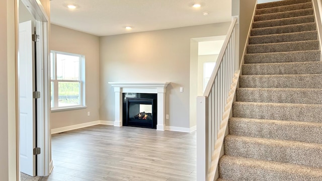 stairs with wood-type flooring and a multi sided fireplace