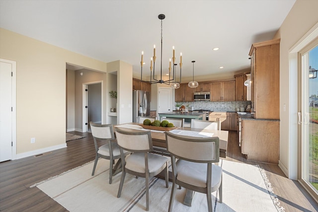 kitchen featuring tasteful backsplash, wood-type flooring, hanging light fixtures, stainless steel appliances, and a notable chandelier