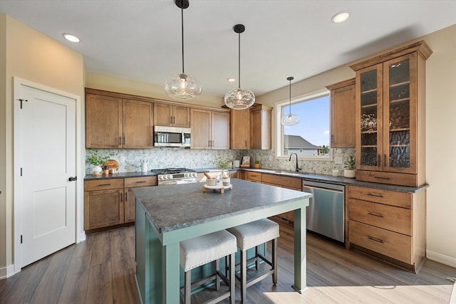 kitchen featuring appliances with stainless steel finishes, sink, a kitchen bar, a kitchen island, and dark wood-type flooring