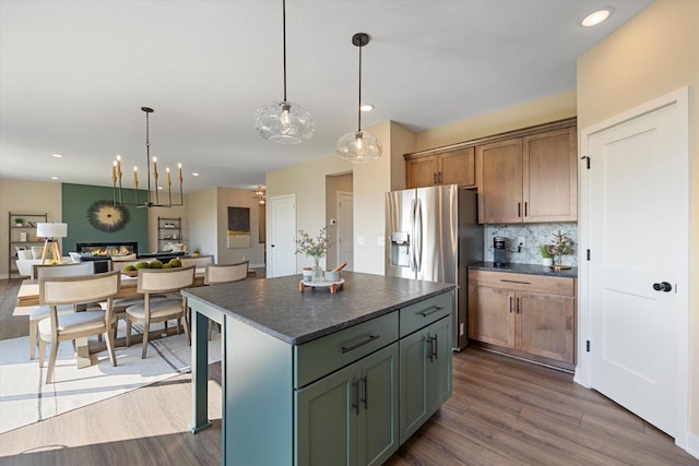 kitchen featuring decorative light fixtures, backsplash, dark wood-type flooring, stainless steel refrigerator with ice dispenser, and a center island