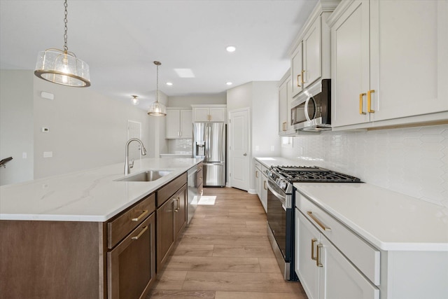 kitchen featuring light hardwood / wood-style flooring, stainless steel appliances, sink, decorative light fixtures, and white cabinets