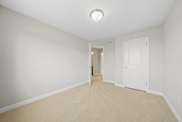 unfurnished bedroom with a closet and light colored carpet