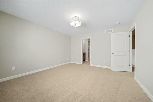 unfurnished bedroom with connected bathroom and light colored carpet