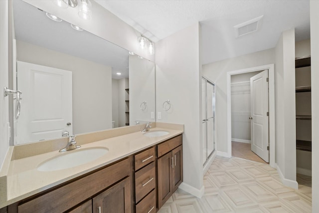 bathroom featuring a shower with door and vanity