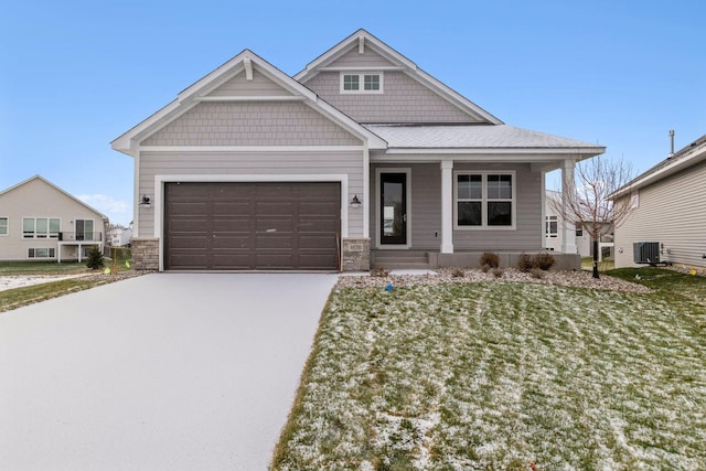 craftsman inspired home featuring cooling unit, a front lawn, and a garage