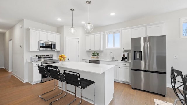 kitchen with decorative light fixtures, sink, white cabinetry, and appliances with stainless steel finishes