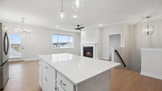 kitchen featuring white cabinetry, stainless steel fridge, hanging light fixtures, and a center island