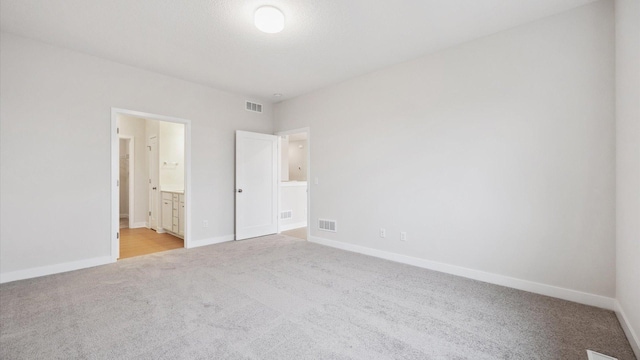 unfurnished bedroom with light colored carpet and ensuite bath