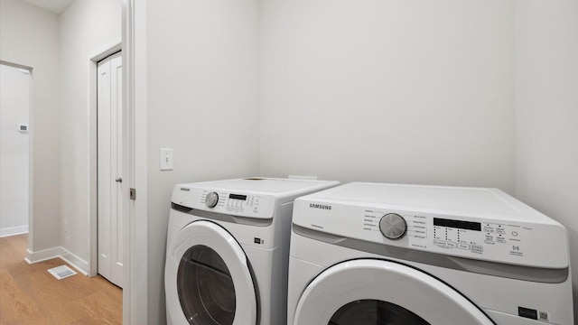 clothes washing area with washer and dryer and light hardwood / wood-style floors